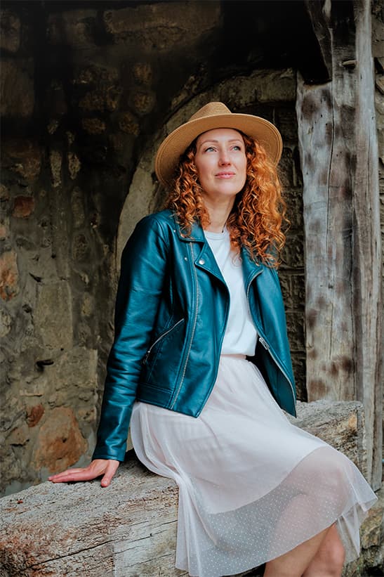 portrait à l'extérieur: femme assise en robe et chapeau avec une veste en cuir